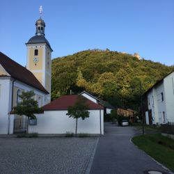 Die Pfarrkirche mit Kopffelsen im Hintergrund